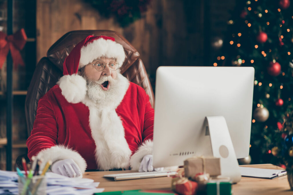 Surprised Santa Claus sitting at desk on computer